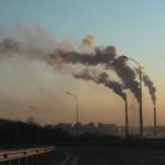 plumes of smoke from power plants above a city skyline