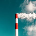 Power plant emitting smoke against a blue sky
