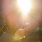 Woman in the sun with her hand to her head, perspiring in the heat